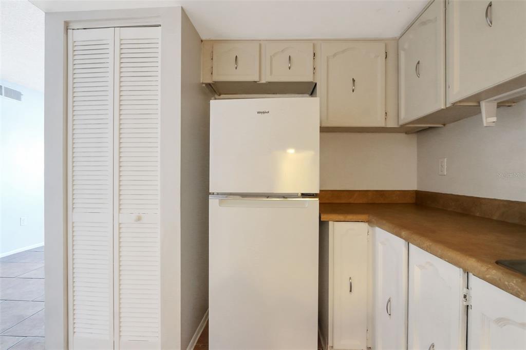 A kitchen features a white refrigerator, beige cabinets, and a brown laminate countertop — 1902 HONOUR ROAD UNIT 11, ORLANDO, FL