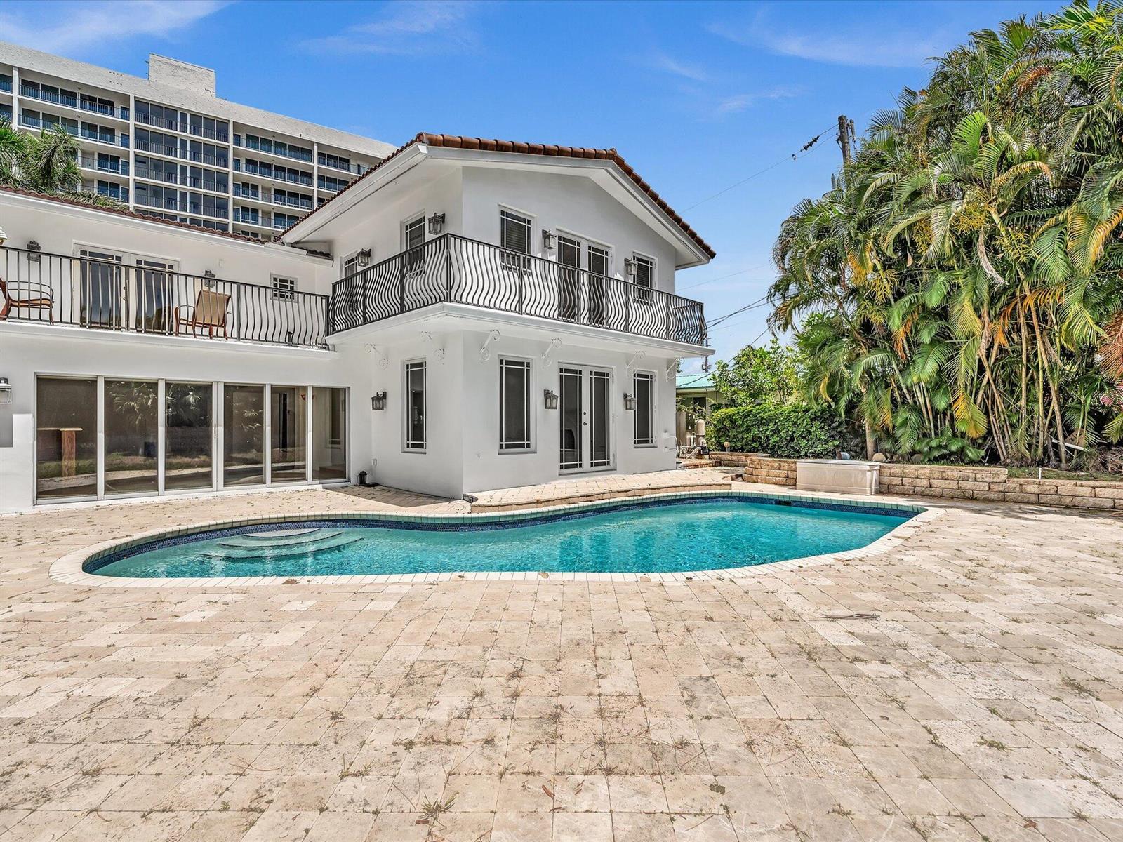 A white two-story house with a balcony and a swimming pool on a stone patio — 518 N Riverside Drive, Pompano Beach FL 33062, POMPANO BEACH, FL