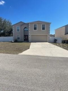 A two-story suburban house with a beige stucco exterior and a two-car garage — 122 FLATFISH COURT, POINCIANA, FL