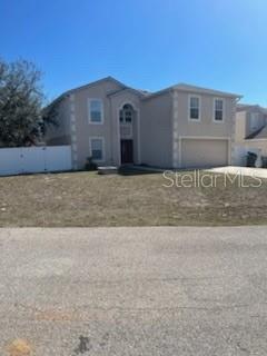 A two-story, light-colored suburban house with a two-car garage and a white fence — 122 FLATFISH COURT, POINCIANA, FL