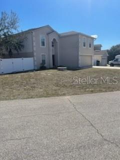 A two-story house with light-colored siding and a white fence stands near a paved road — 122 FLATFISH COURT, POINCIANA, FL