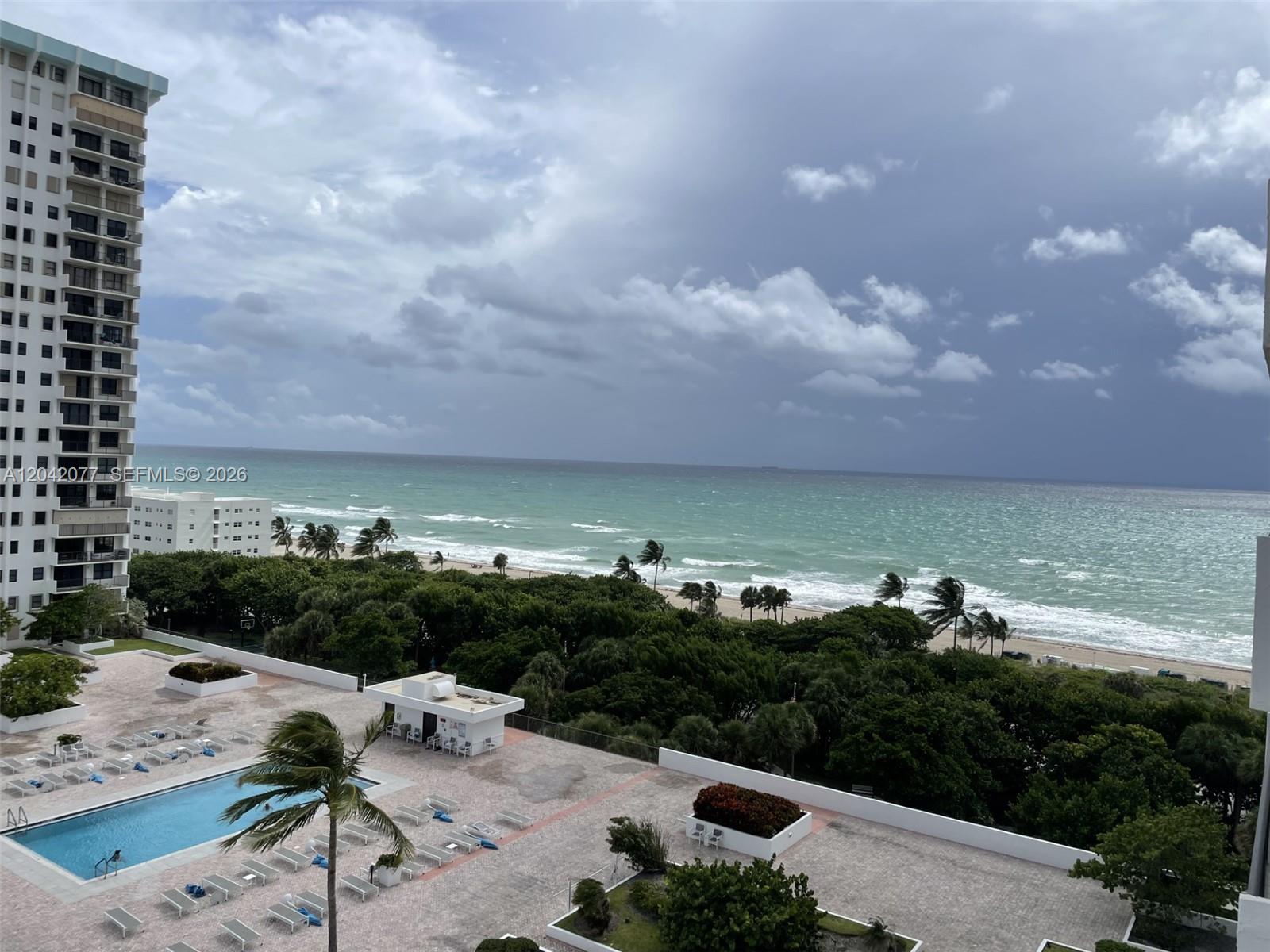 An elevated view shows a swimming pool, palm trees, and a beach along the ocean — 1201 S Ocean Dr # 1107S, Hollywood FL 33019, HOLLYWOOD, FL