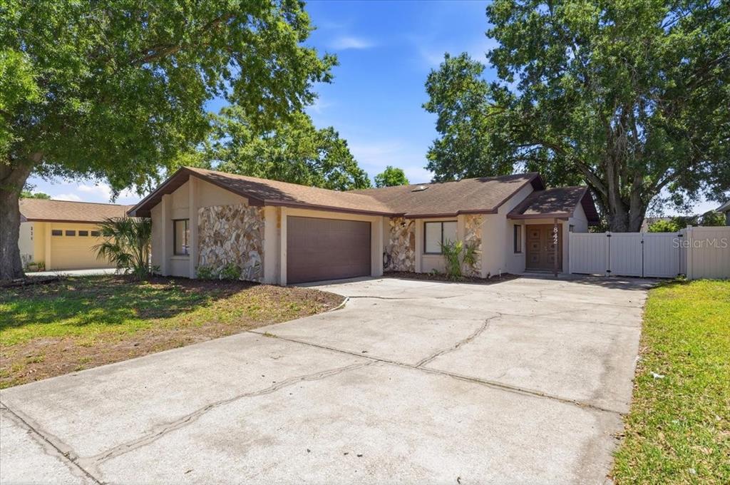 A single-story house with a stone facade, brown garage door, and a concrete driveway — 842 ROCKINGHAM ROAD, LAKELAND, FL