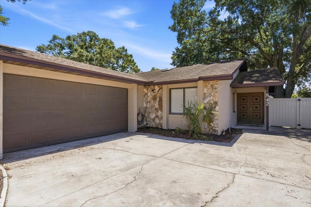 A single-story house features a brown garage door, stone accents, and a double front door — 842 ROCKINGHAM ROAD, LAKELAND, FL