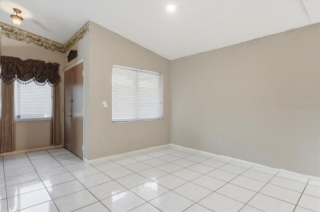 A room with white tiled floors, beige walls, a window with blinds, and a door — 842 ROCKINGHAM ROAD, LAKELAND, FL