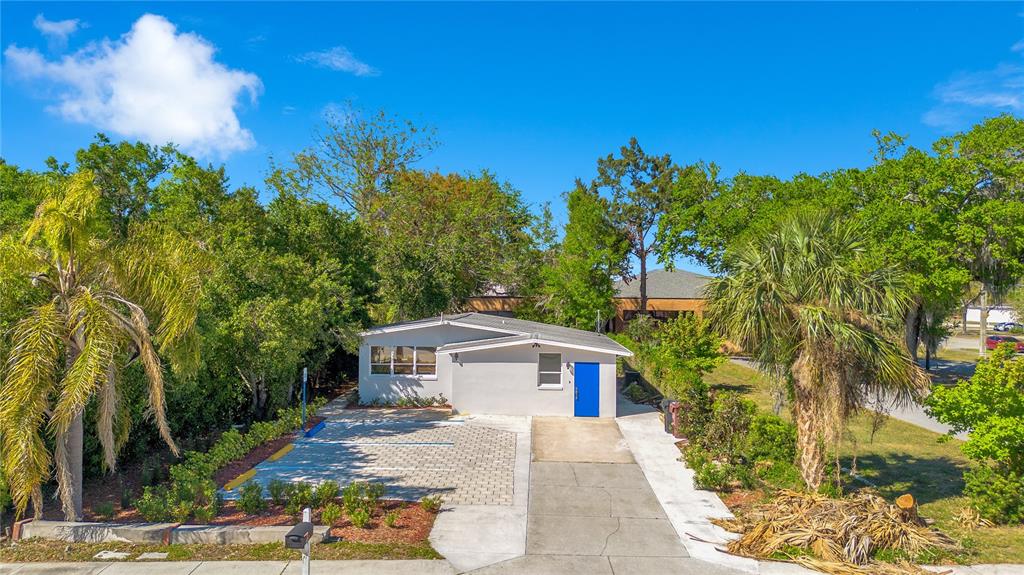 A single-story house with a blue door, a paved parking area, and surrounding trees — 4749 HARGRAVE STREET, ORLANDO, FL
