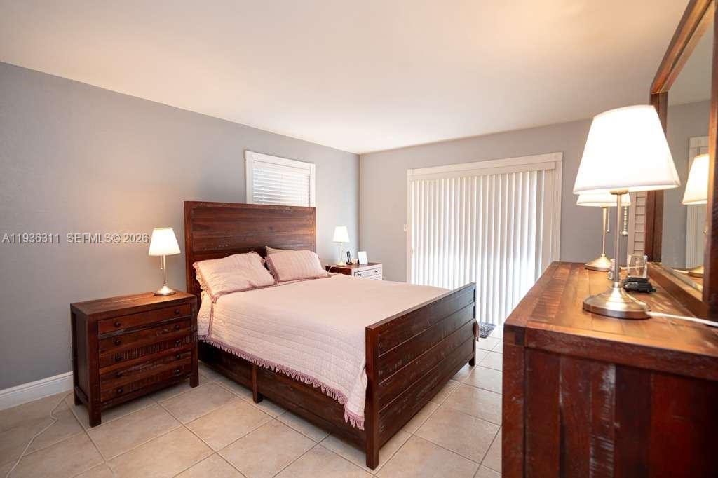 A bedroom features a wooden bed frame, matching nightstands, a dresser, and tile flooring — 8600 SW 109th Ave # 114, Miami FL 33173, MIAMI, FL