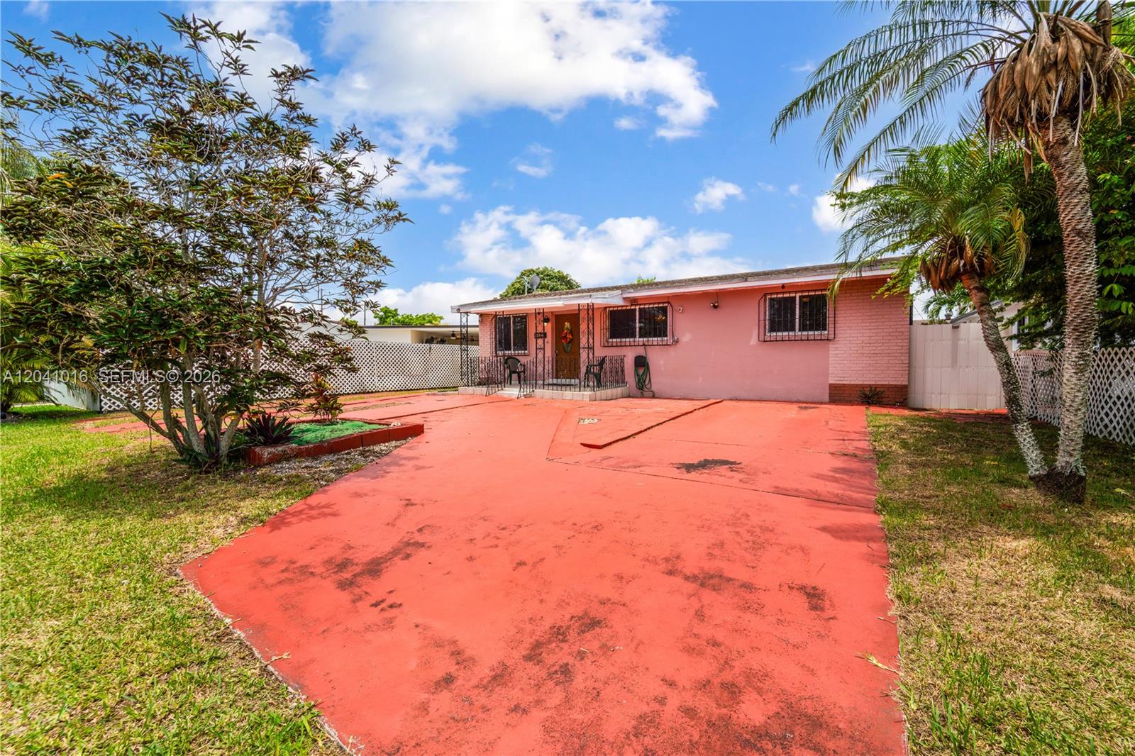 A single-story pink house features a large red concrete driveway and a palm tree — 11941 SW 4th St, Miami FL 33184, MIAMI, FL