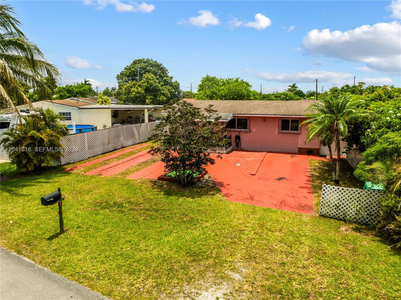 A pink single-story house features a red painted driveway and a large front lawn — 11941 SW 4th St, Miami FL 33184, MIAMI, FL