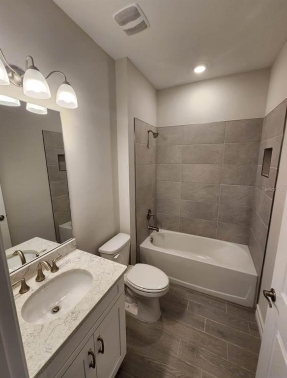 A bathroom features a vanity with a stone countertop, a toilet, and a tiled tub-shower — 333 VILLORESI BOULEVARD, NOKOMIS, FL