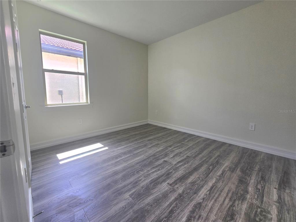 An empty bedroom features light-colored walls, gray wood-look flooring, and a single window — 333 VILLORESI BOULEVARD, NOKOMIS, FL