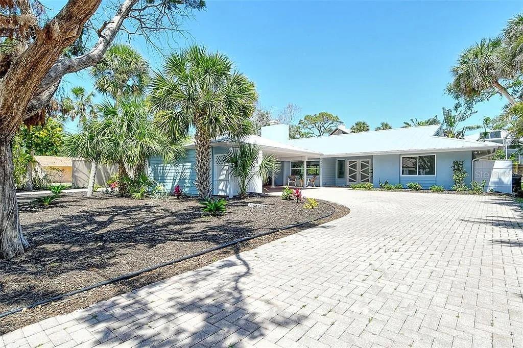 A single-story house with a light blue exterior and a paved driveway under a clear sky — 4852 FEATHERBED LANE, SARASOTA, FL