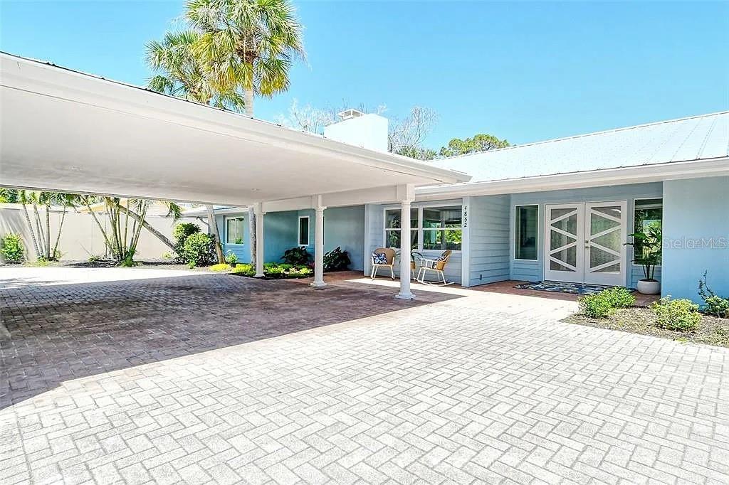 A paved driveway leads to a covered carport and the entrance of a blue house — 4852 FEATHERBED LANE, SARASOTA, FL
