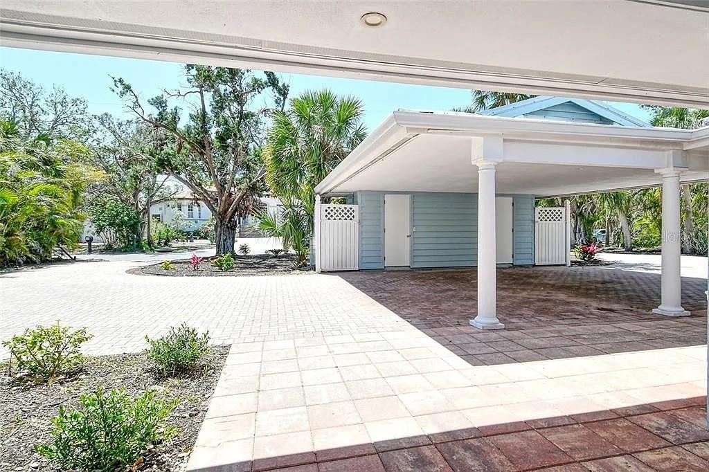 A paved driveway leads to a covered carport with white columns and light blue siding — 4852 FEATHERBED LANE, SARASOTA, FL