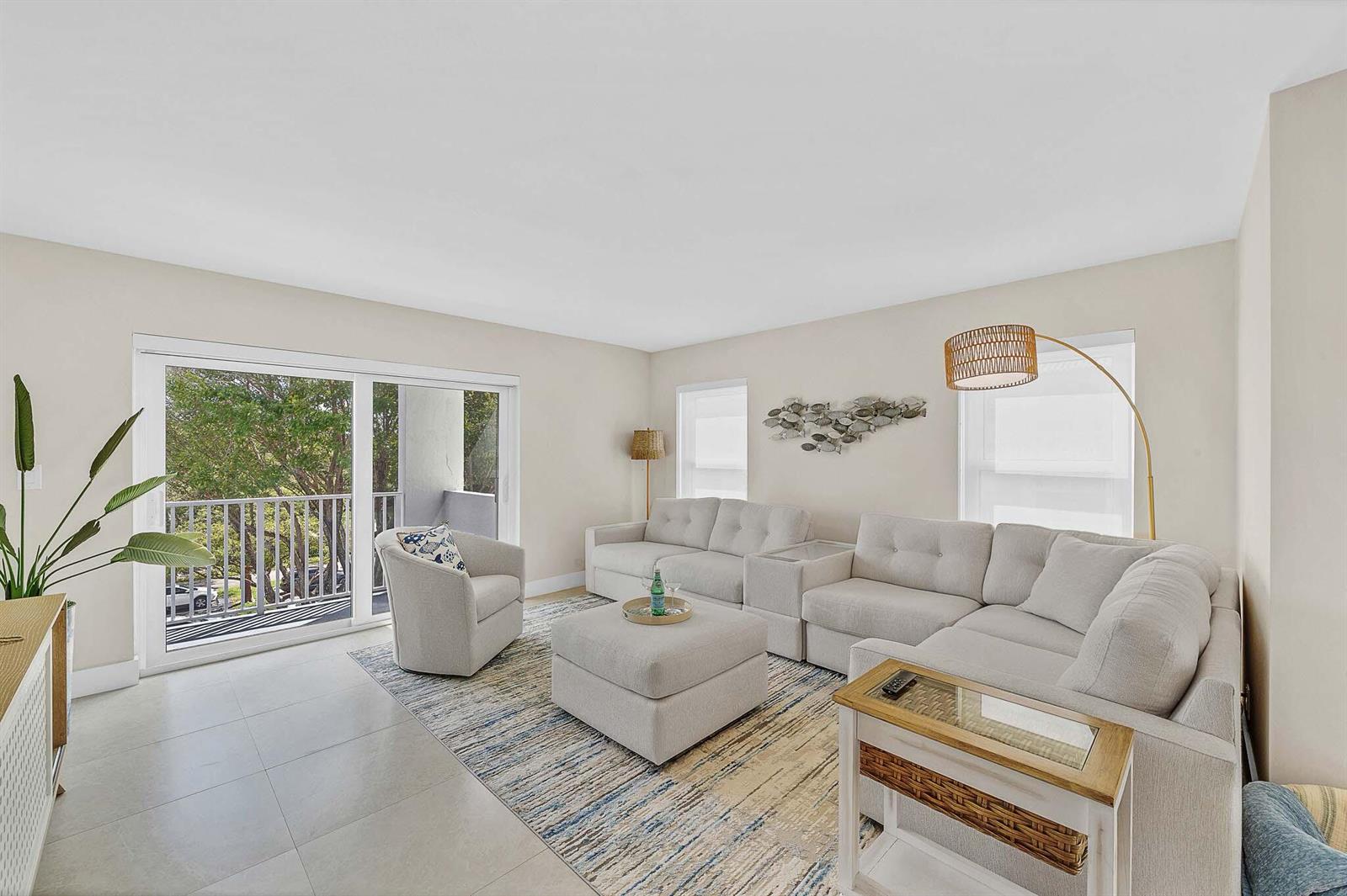 A living room features a light-colored sectional sofa, an armchair, an ottoman, and a balcony — 1111 S Ocean Boulevard # 414, Boca Raton FL 33432, BOCA RATON, FL