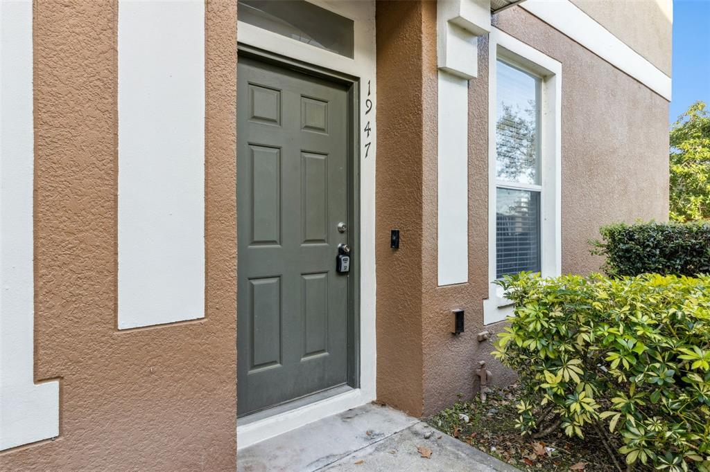 A front exterior view shows a brown door with a lockbox and house number 1947 — 1947 ESTANCIA CIRCLE UNIT 8C, KISSIMMEE, FL