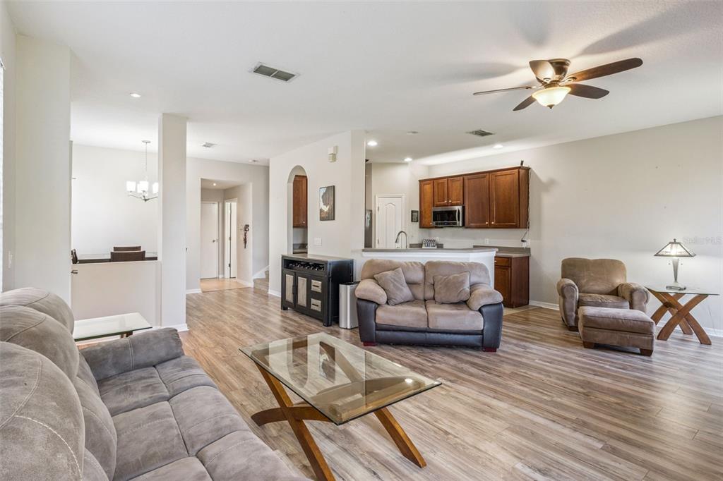 A living room with wood-look flooring, a glass coffee table, and an open kitchen area — 1947 ESTANCIA CIRCLE UNIT 8C, KISSIMMEE, FL