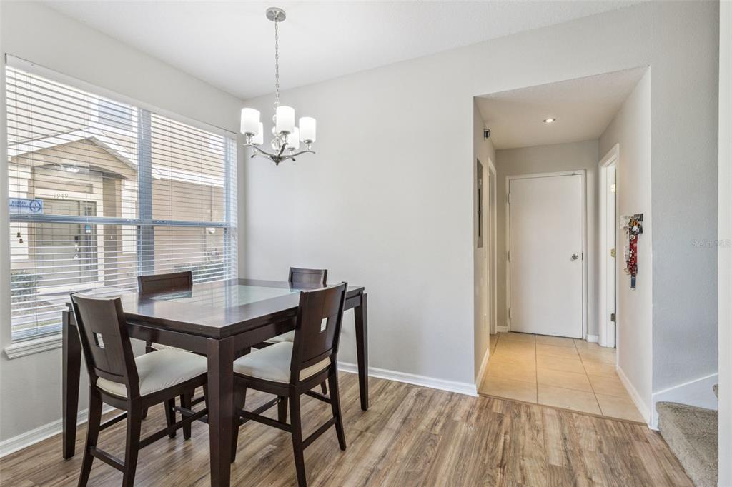A dining area with a dark wood table, chairs, and a chandelier near a window — 1947 ESTANCIA CIRCLE UNIT 8C, KISSIMMEE, FL