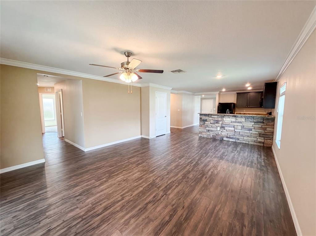An open-concept living area features wood-look flooring, a stone-faced kitchen island, and a ceiling fan — 1880 PIEDMONT COURT, MASCOTTE, FL