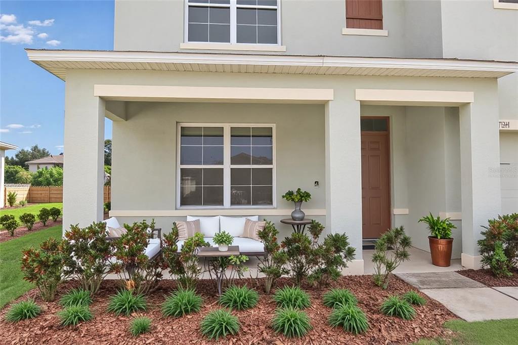 A covered front porch features a white bench, potted plants, and a brown door — 3228 COUNTRY WALK CLUB CIRCLE, WINTER HAVEN, FL
