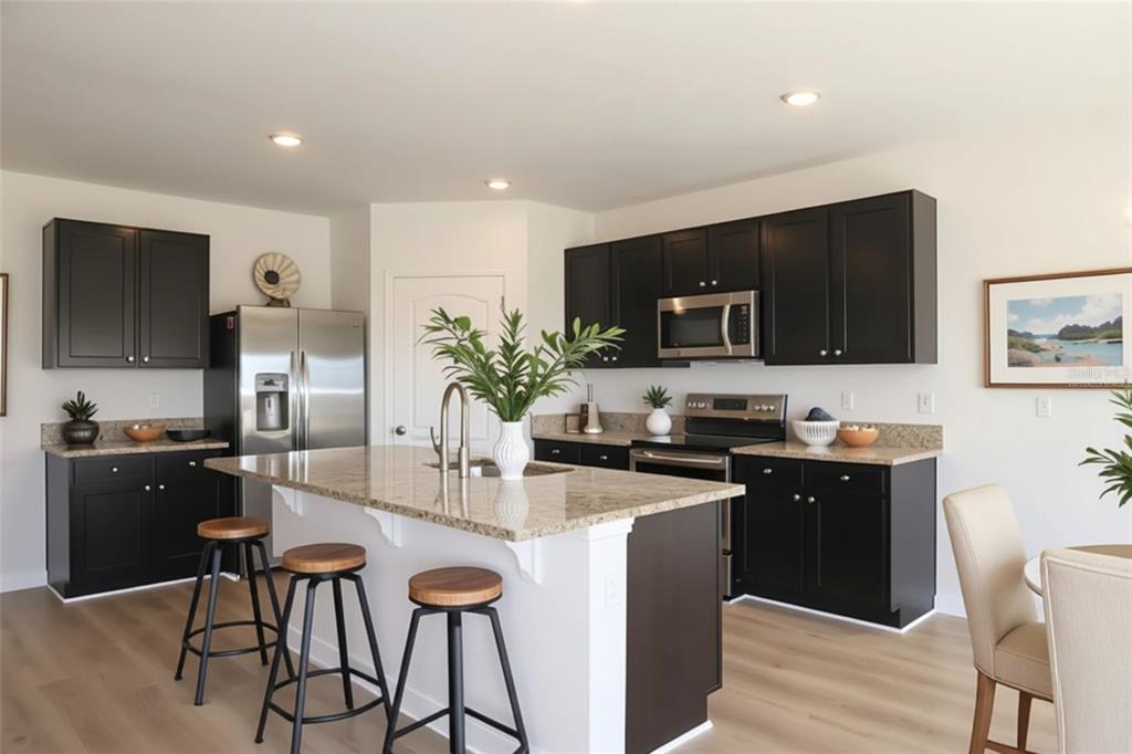 A kitchen with dark cabinets, granite countertops, a central island with stools, and stainless appliances — 3228 COUNTRY WALK CLUB CIRCLE, WINTER HAVEN, FL