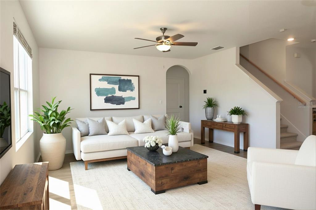 A living room features a white sofa, a wooden coffee table, and a staircase — 3228 COUNTRY WALK CLUB CIRCLE, WINTER HAVEN, FL