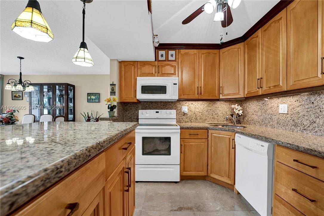 A kitchen features light wood cabinets, granite countertops, and white appliances — 1400 S Ocean Dr # 1004, Hollywood FL 33019, HOLLYWOOD, FL