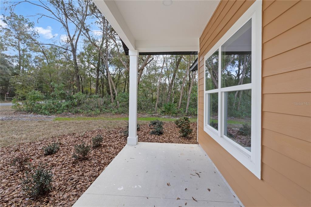 A modern white farmhouse with a black roof and garage sits on a grassy lot — 11380 NW 92ND CT, CHIEFLAND, FL