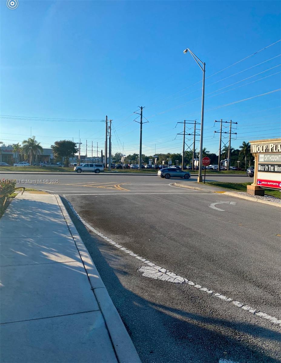 A view of a paved commercial parking lot entrance leading to a road with traffic — 5360 S University Dr, Davie FL 33328, DAVIE, FL