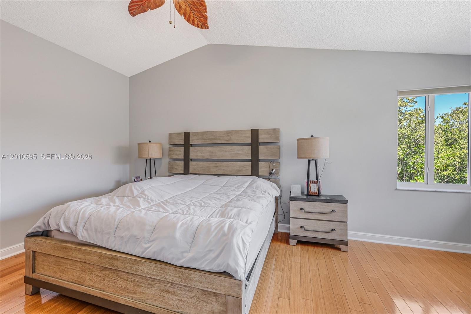 A bedroom features a wooden bed frame, two nightstands with lamps, and light-colored walls — 1065 Weeping Willow Way, Hollywood FL 33019, HOLLYWOOD, FL