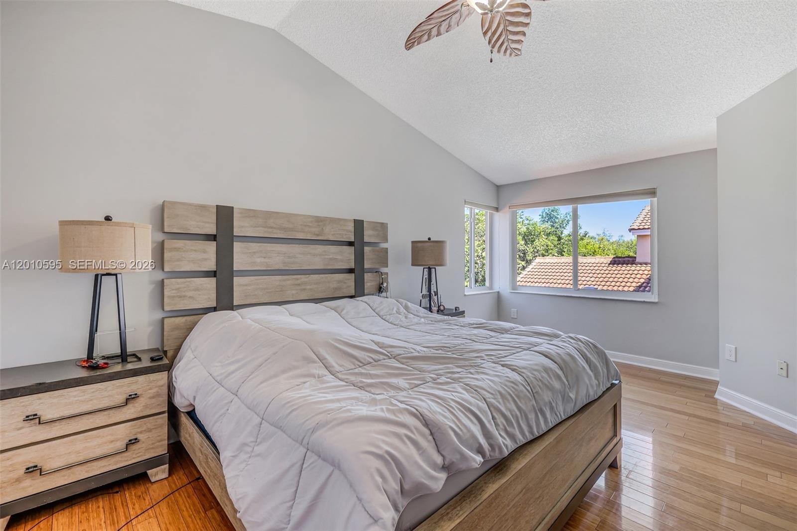 A bedroom features a wooden bed frame, a vaulted ceiling, and a view of rooftops — 1065 Weeping Willow Way, Hollywood FL 33019, HOLLYWOOD, FL