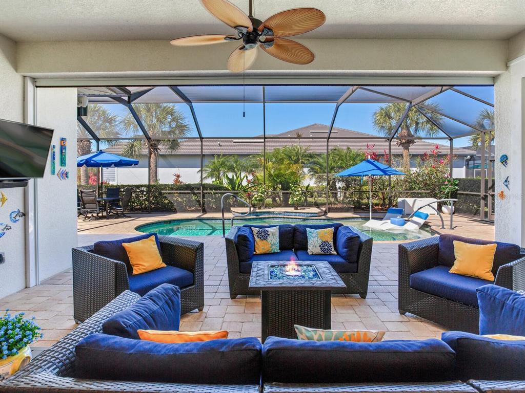 A covered patio features outdoor furniture, a fire pit, and a screened-in swimming pool — 5611 TIDEWATER PRESERVE BOULEVARD, BRADENTON, FL