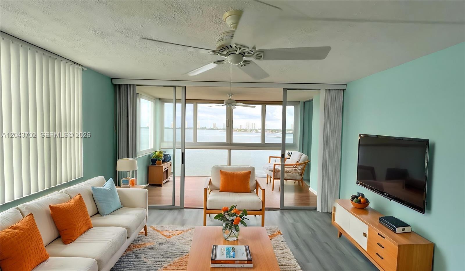 A living room with light blue walls, a white sofa, and sliding doors opening to a balcony — 401 Lake Shore Dr # 801, Lake Park FL 33403, LAKE PARK, FL
