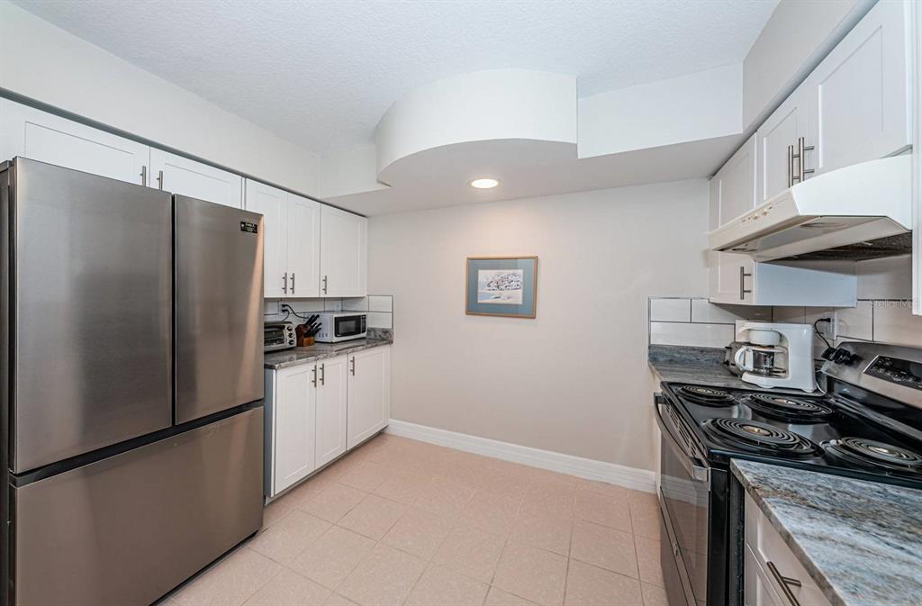 A kitchen featuring white cabinets, stainless steel appliances, and a light-colored tiled floor — 6061 BAHIA DEL MAR CIRCLE UNIT 448, ST PETERSBURG, FL