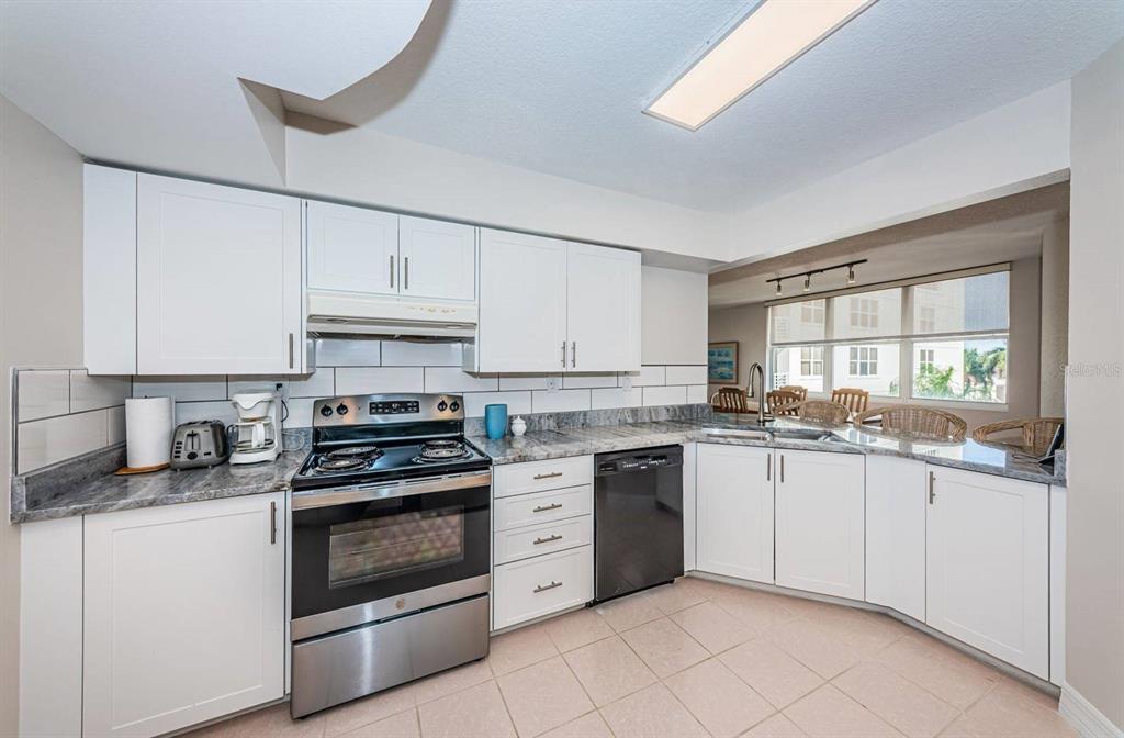 A kitchen with white cabinets, stainless steel appliances, and gray granite countertops — 6061 BAHIA DEL MAR CIRCLE UNIT 448, ST PETERSBURG, FL