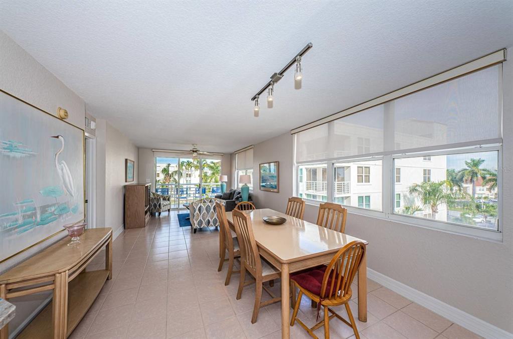 A dining area with a light-colored table and chairs sits beside large windows and tile floors — 6061 BAHIA DEL MAR CIRCLE UNIT 448, ST PETERSBURG, FL