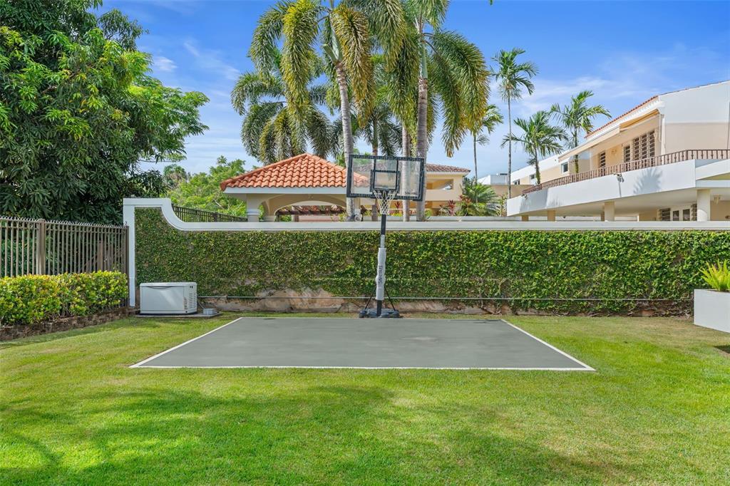 A backyard features a small concrete basketball court set in a grassy lawn with landscaping — 11 VIAJERA UNIT 76, GUAYNABO, PR