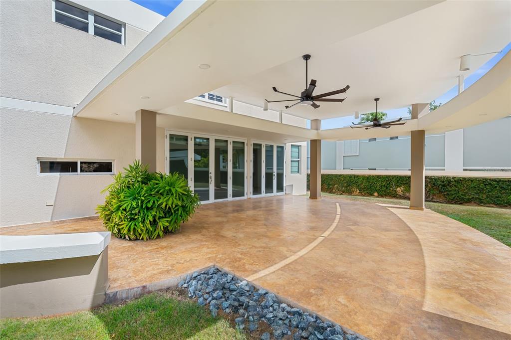 A covered patio with a curved stone floor, ceiling fans, and glass folding doors — 11 VIAJERA UNIT 76, GUAYNABO, PR