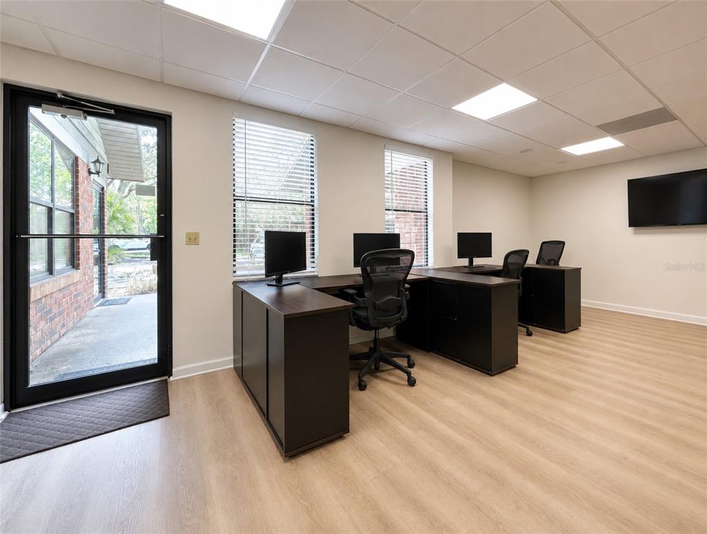 An office space features two dark L-shaped desks, rolling chairs, and light wood-look flooring — 2731 NW 41ST STREET UNIT B2, GAINESVILLE, FL