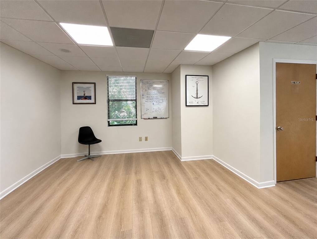 An office room features light wood-look flooring, a white whiteboard, a black chair, and an anchor print — 2731 NW 41ST STREET UNIT B2, GAINESVILLE, FL