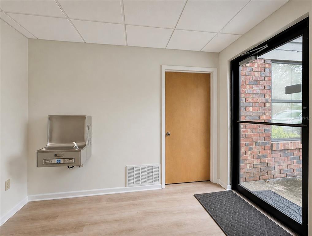 An interior office space features a water fountain, a wooden door, and a glass entrance door — 2731 NW 41ST STREET UNIT B2, GAINESVILLE, FL