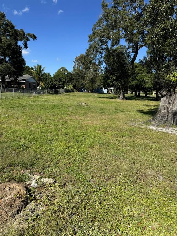 A grassy, vacant lot features several large trees and a distant house behind a fence — 201 N 29TH STREET, FORT PIERCE, FL
