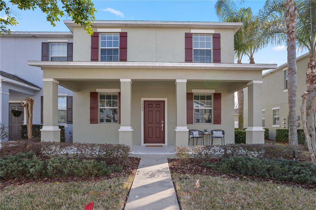 A two-story house with a covered front porch, tan stucco siding, and maroon shutters — 1264 SEBURN ROAD, APOPKA, FL