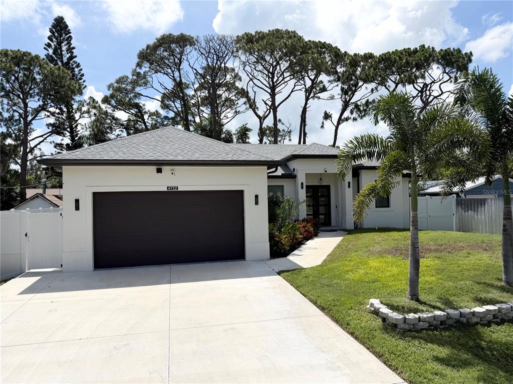 A single-story house with a white exterior, a dark garage door, and a palm tree — 4722 NEPTUNE ROAD, VENICE, FL