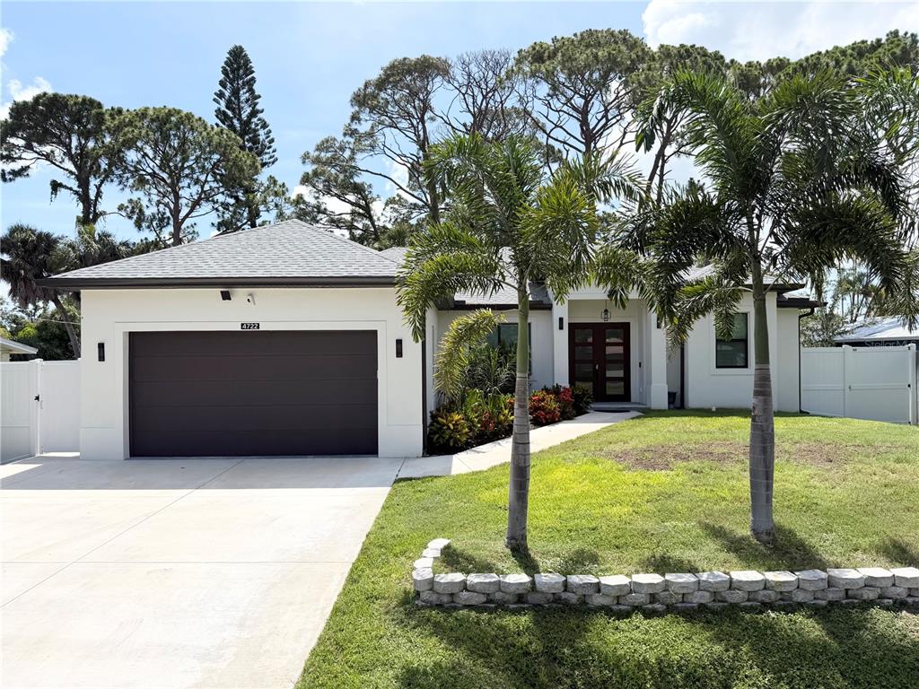 A single-story house with a white exterior, dark garage door, and two palm trees — 4722 NEPTUNE ROAD, VENICE, FL