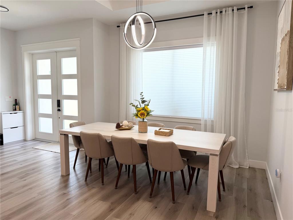A dining room features a light wood table, six upholstered chairs, and a modern pendant light — 4722 NEPTUNE ROAD, VENICE, FL