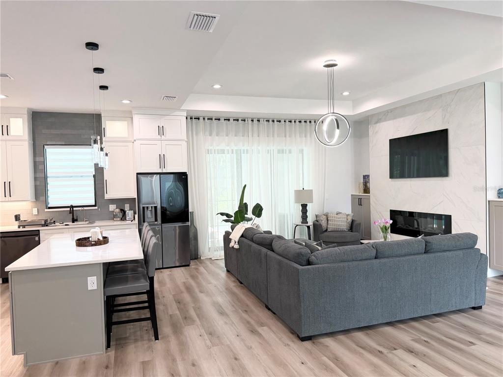 An open-concept kitchen and living area features white cabinetry, a gray island, and a fireplace — 4722 NEPTUNE ROAD, VENICE, FL