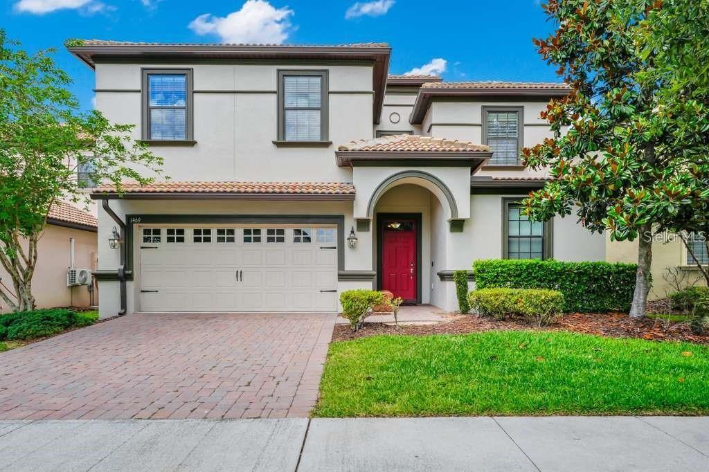 A two-story house with a red front door, a two-car garage, and a brick driveway — 1469 ROLLING FARIWAY, DAVENPORT, FL