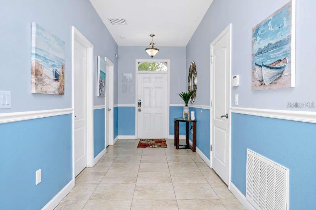 A bright entryway features light blue walls with white wainscoting, tile flooring, and a door — 1469 ROLLING FARIWAY, DAVENPORT, FL