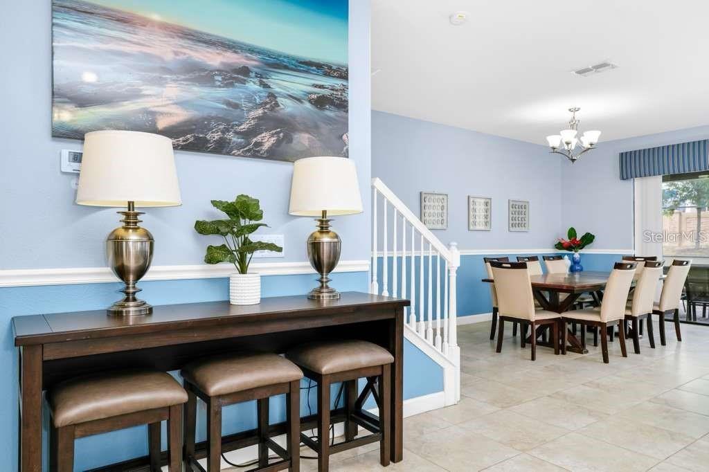 A dining area with a console table, stools, and a staircase in a light blue room — 1469 ROLLING FARIWAY, DAVENPORT, FL